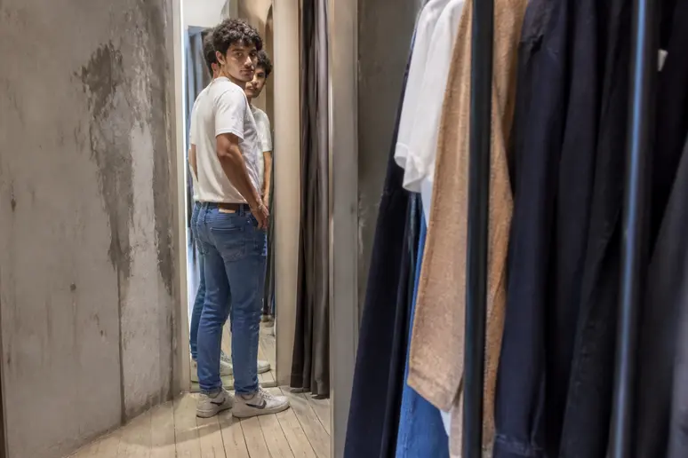 Un jeune homme français essaie un jean Levi's 512 dans une boutique, évaluant la coupe ajustée et moderne devant le miroir.