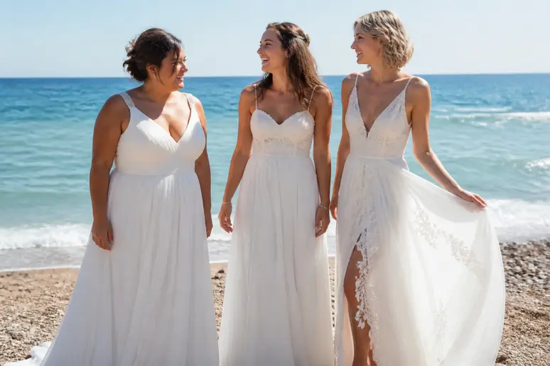 Essai de robes de mariée simples de plage adaptées à différentes morphologies, sur une plage ensoleillée du sud de la France.