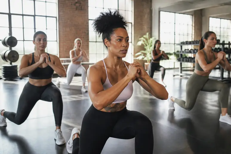 Des femmes toniques en tenue de sport pratiquent le body sculpt en groupe pour sculpter leur silhouette.