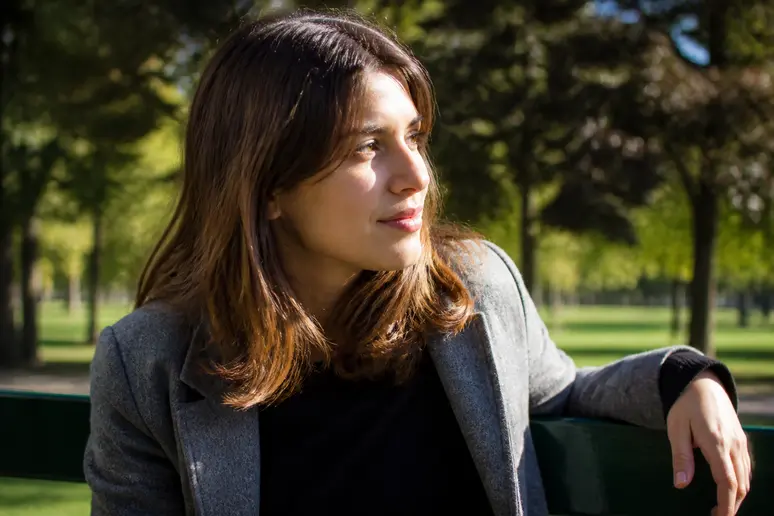 Femme aux cheveux châtain balayage caramel en extérieur, reflets solaires doux.