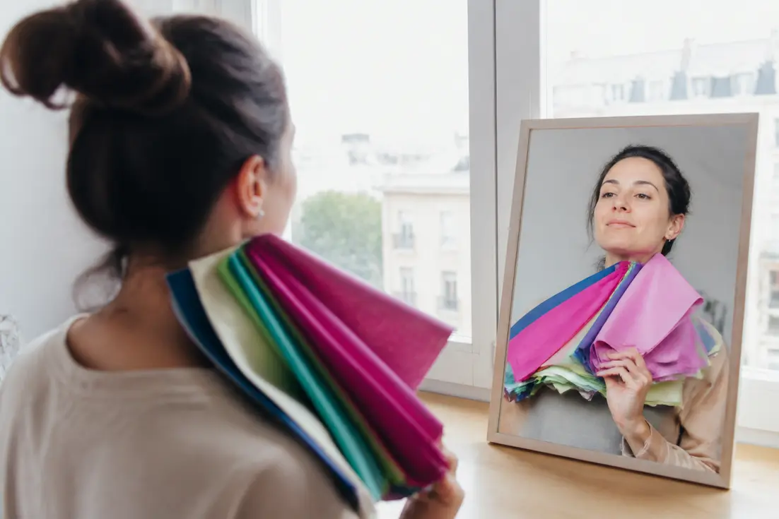 Une femme réalise un test colorimétrie femme printemps avec des tissus colorés devant la lumière naturelle