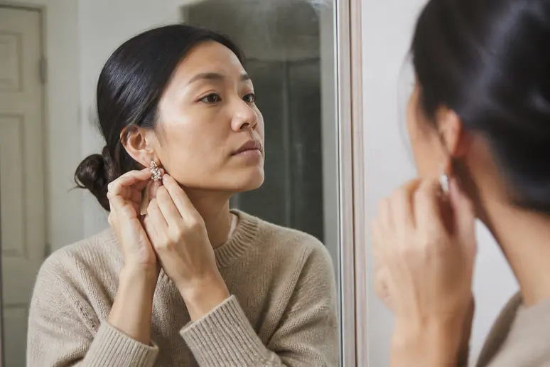 Personne ajoutant des boucles d'oreilles scintillantes sur un pull simple pour une tenue de Noël chic