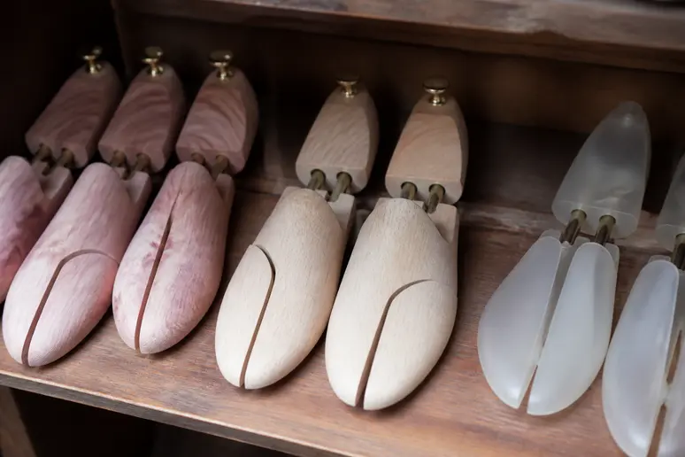 Différents embauchoirs pour chaussures en bois et plastique, exposés en gros plan.