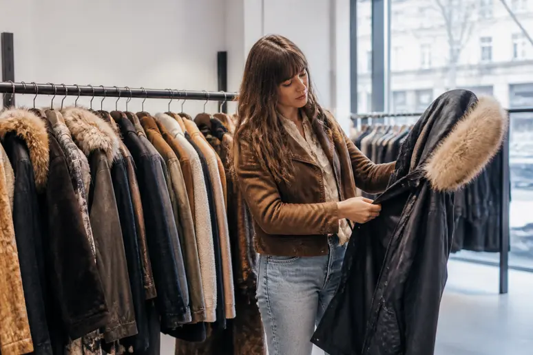 Femme choisissant un manteau parka IKKS femme dans une boutique élégante.
