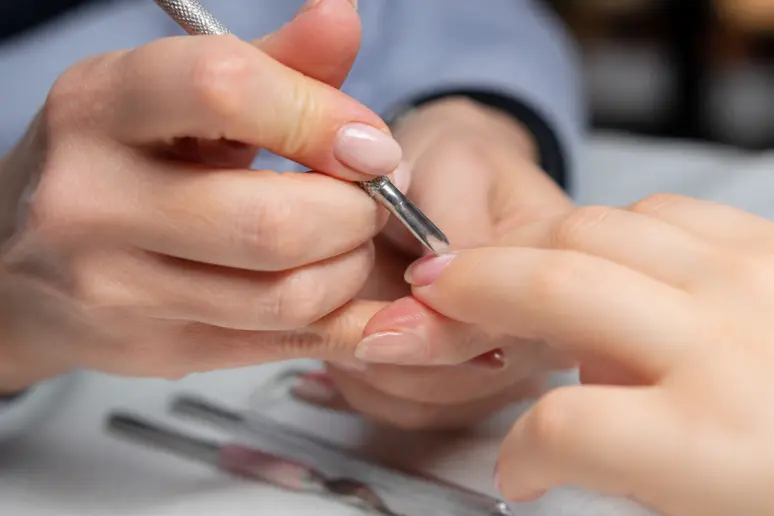 Préparation minutieuse d'un ongle naturel pour une pose d'ongle au chablon avec outils.