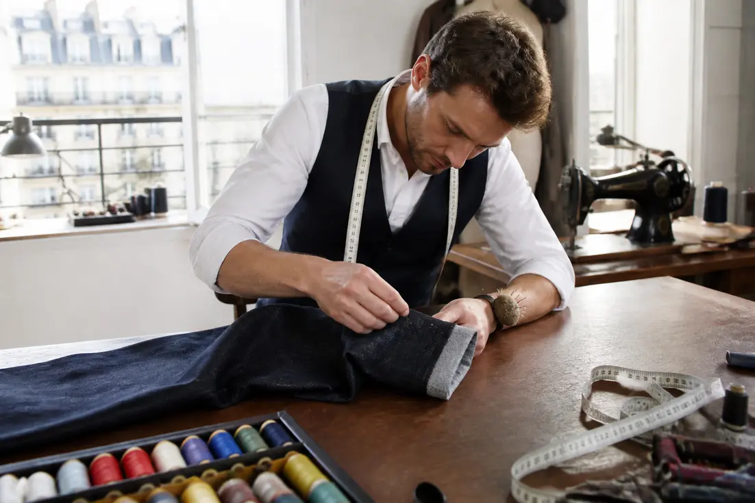 Un tailleur ajuste un pantalon pour évaluer le prix ourlet pantalon dans un atelier de couture