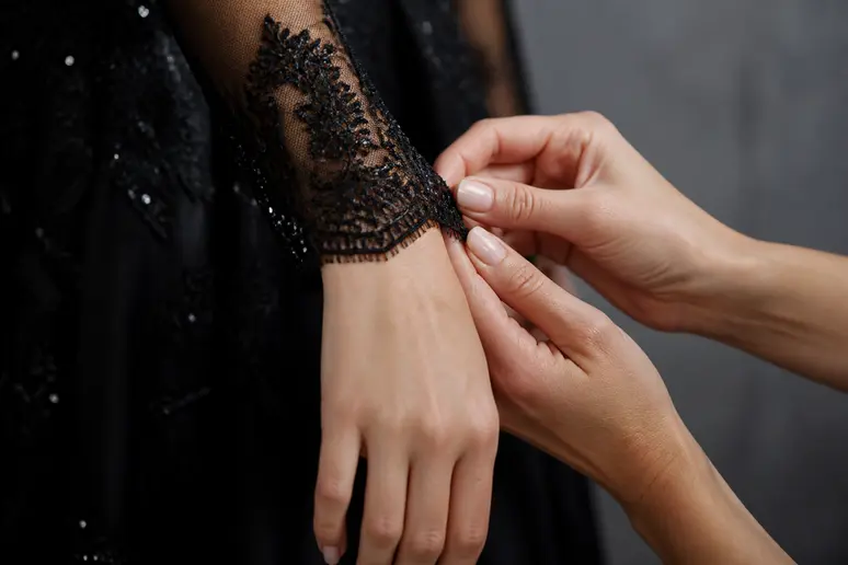 Détail minutieux d'une manche de robe de mariée noire avec une manchette en dentelle, soulignant le style.