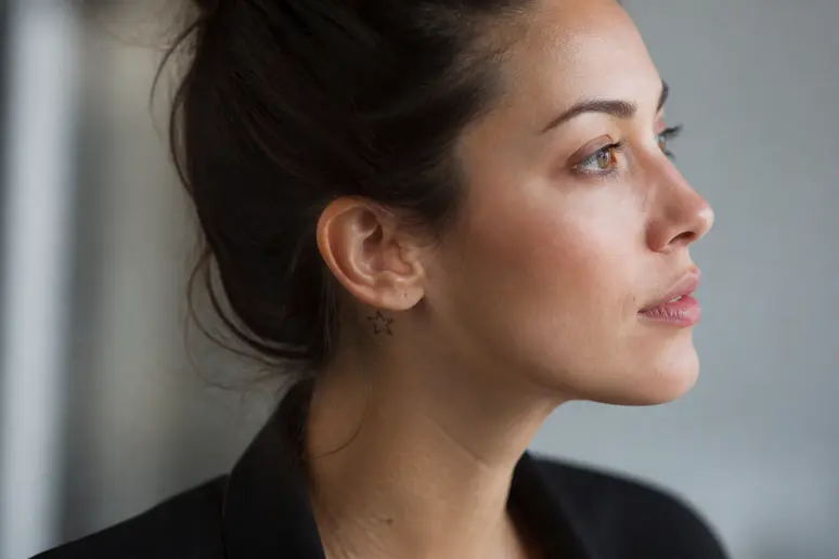 Signification tatouage derriere oreille : une femme dévoile un micro-tatouage discret en étoile.