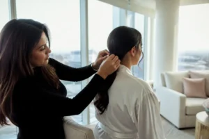 Une coiffeuse ajuste une élégante coiffure mariage queue de cheval basse sur une mariée