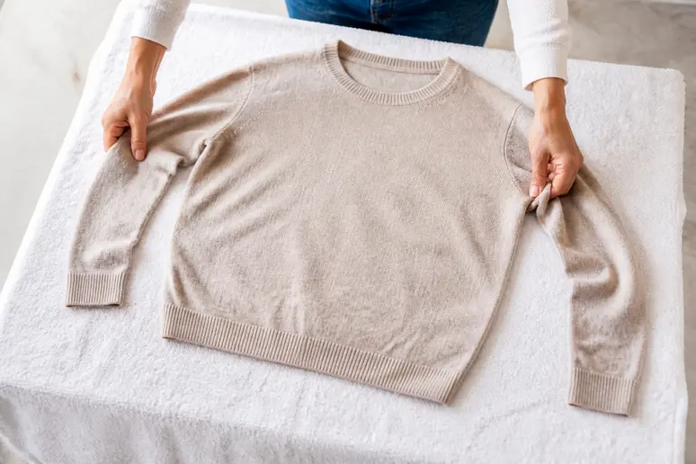 Mise à plat horizontale d'un pull en cachemire sur une serviette propre pour le séchage