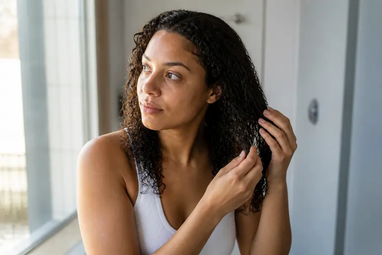 Application minutieuse du leave in cheveux bouclés mèche par mèche sur cheveux humides
