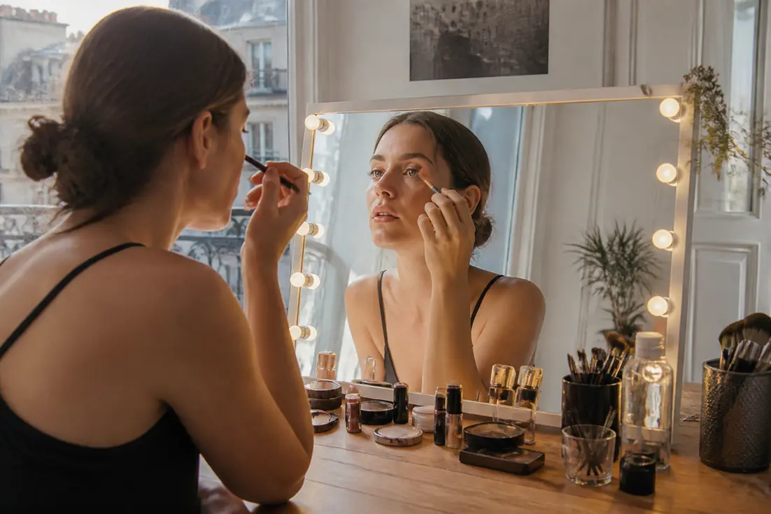Femme appliquant son maquillage paupiere tombante ouvrir regard devant un miroir lumineux