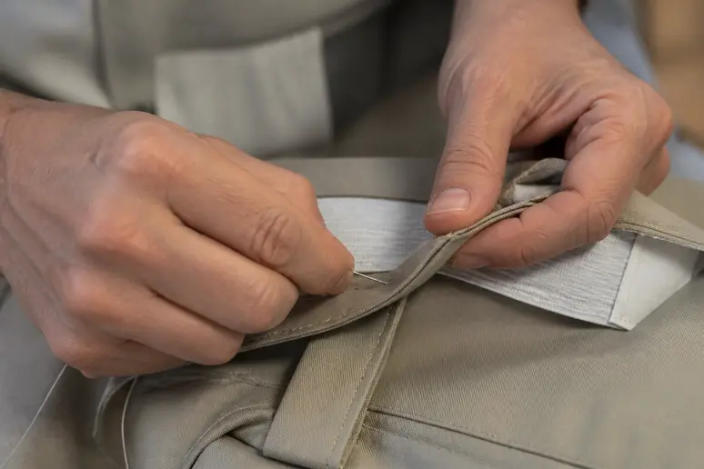 Insertion d'un élastique invisible dans la ceinture arrière d'un pantalon pour ajuster la taille.