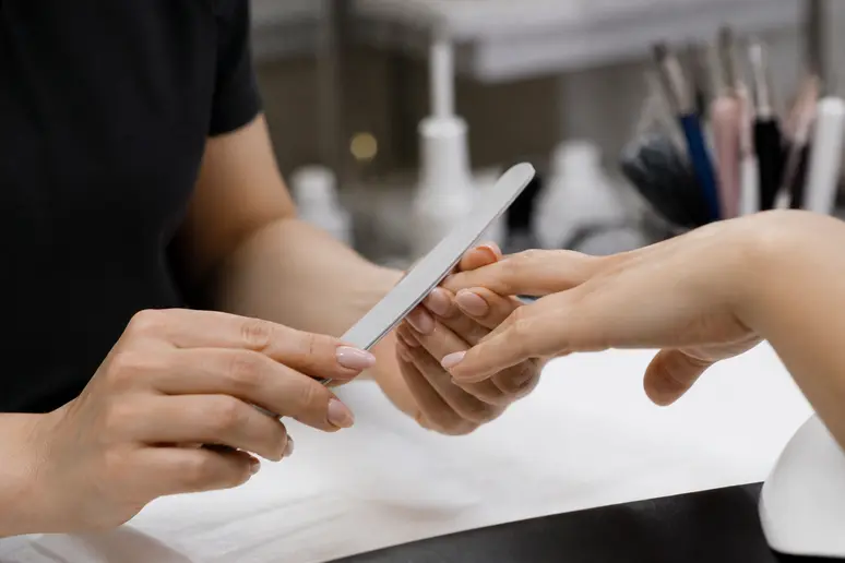 Limage minutieux d'un ongle naturel lors de la préparation d'une pose américaine en salon.