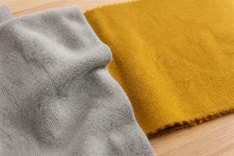 Échantillon de tissu gris clair associé à une nuance jaune moutarde lumineuse sur une table en bois