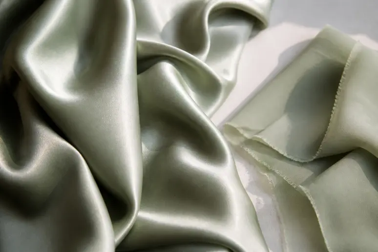 Tissus de robe invitée mariage vert sauge en satin et mousseline sous la lumière naturelle