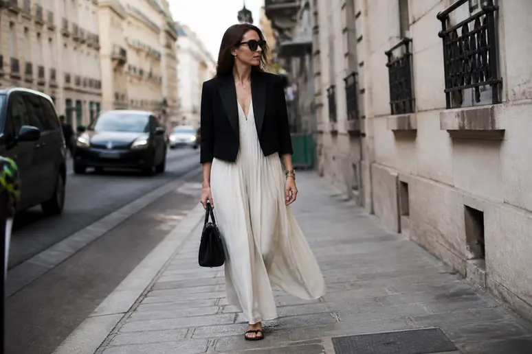 Femme portant une veste courte cintrée sur une robe longue fluide pour structurer la silhouette.