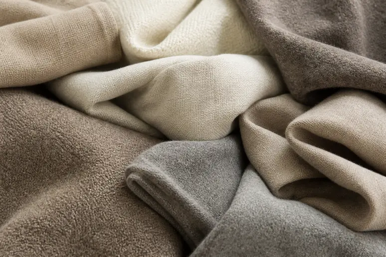 Piles de vêtements aux matières naturelles et aux teintes neutres pour harmoniser sa garde-robe