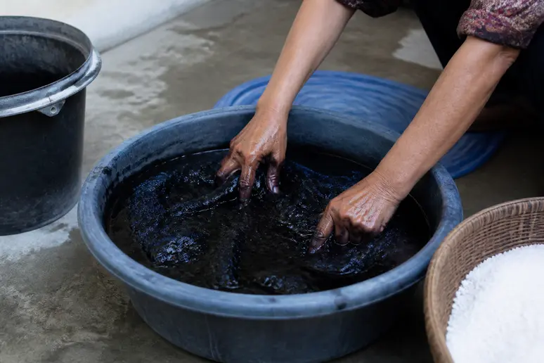 Immersion d'un vêtement dans une bassine d'eau chaude avec de la teinture noire vêtement durable