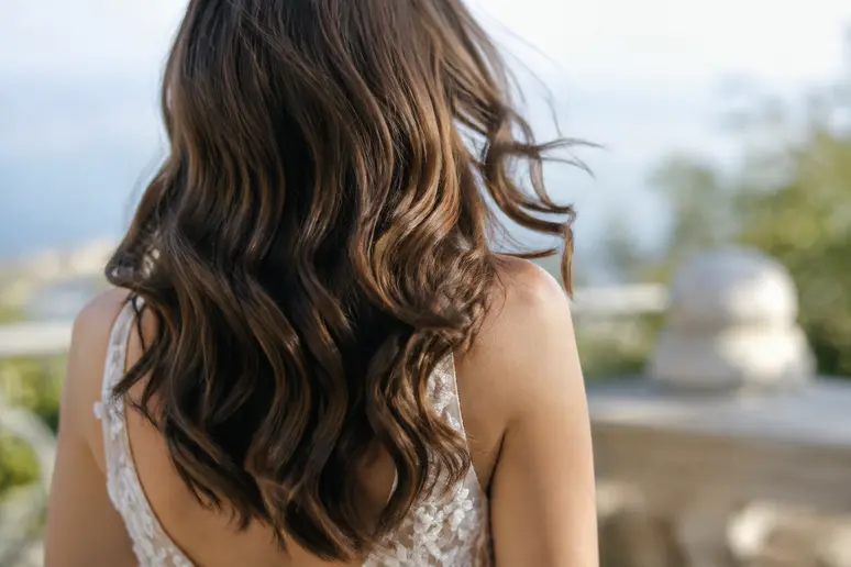 Coiffure de mariage avec des cheveux détachés et ondulés portés souplement sur les épaules.