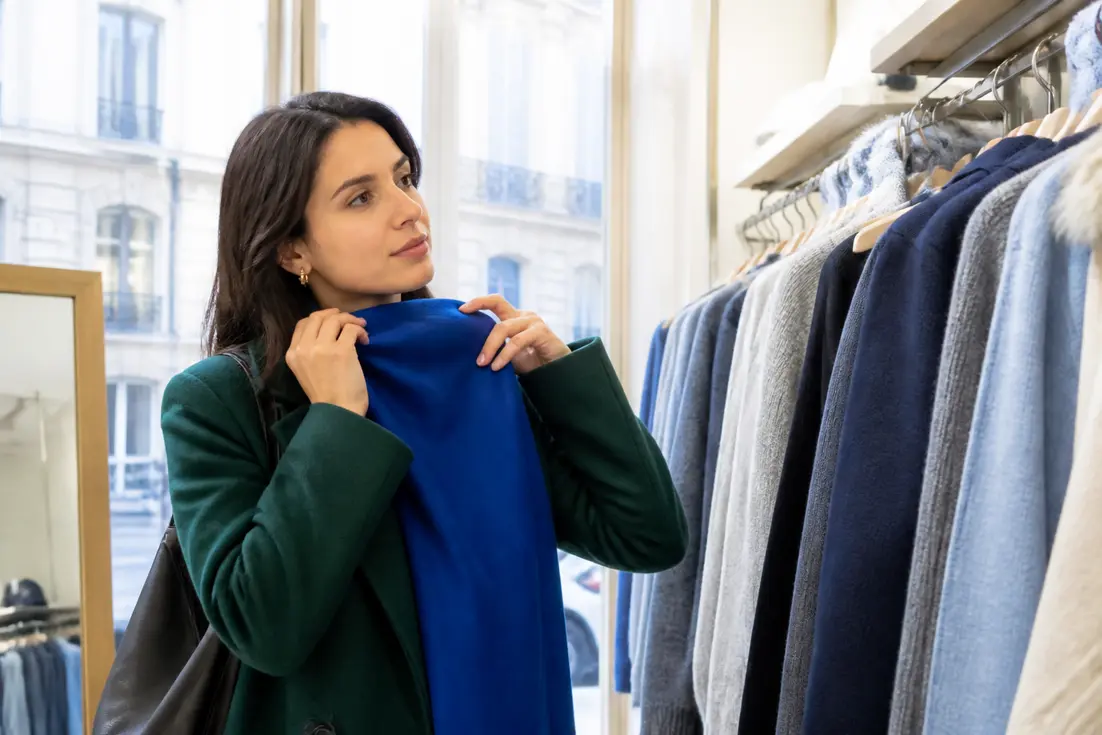 Femme essayant des vêtements aux tons froids avec une colorimétrie hiver vêtements maquillage adaptée à son profil