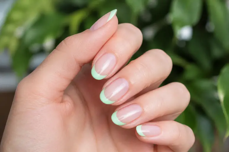 Main avec des ongles courts présentant un liseré pastel fin et délicat sur le bord libre