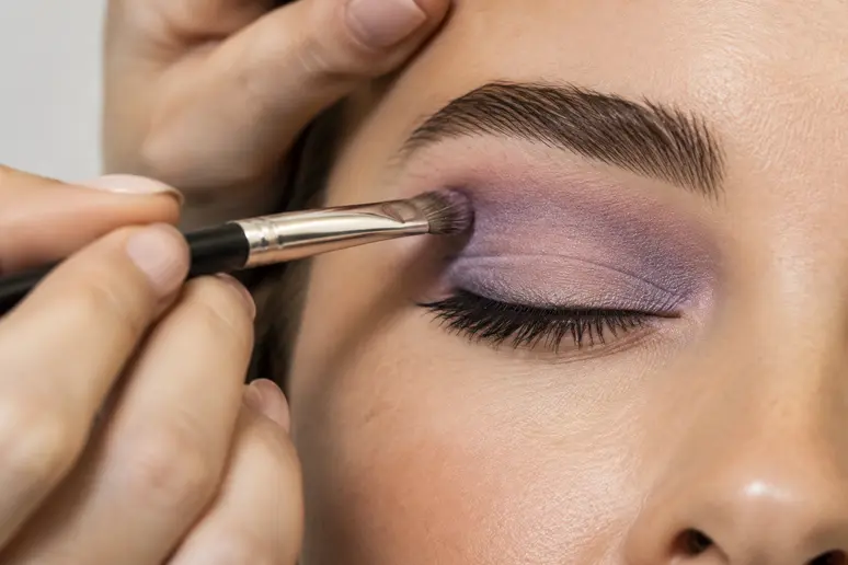 Application d'un fard à paupières violet pour maquillage des yeux marron avec un pinceau fin