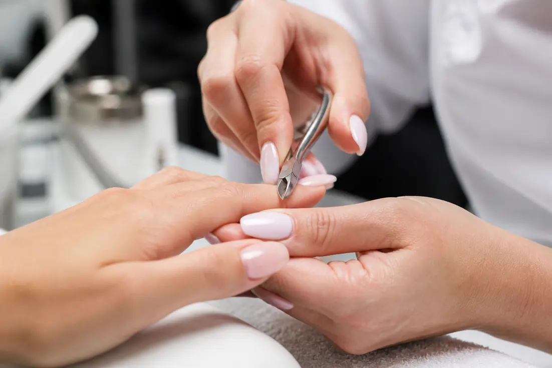 Une prothésiste ongulaire utilise un petit outil métallique lors d'une séance de pinchage définition explication en salon.