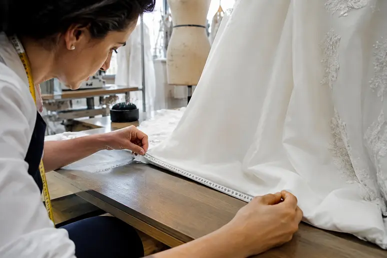 Mesure précise pour l'ourlet d'une robe de mariée lors d'une séance de retouche sur-mesure