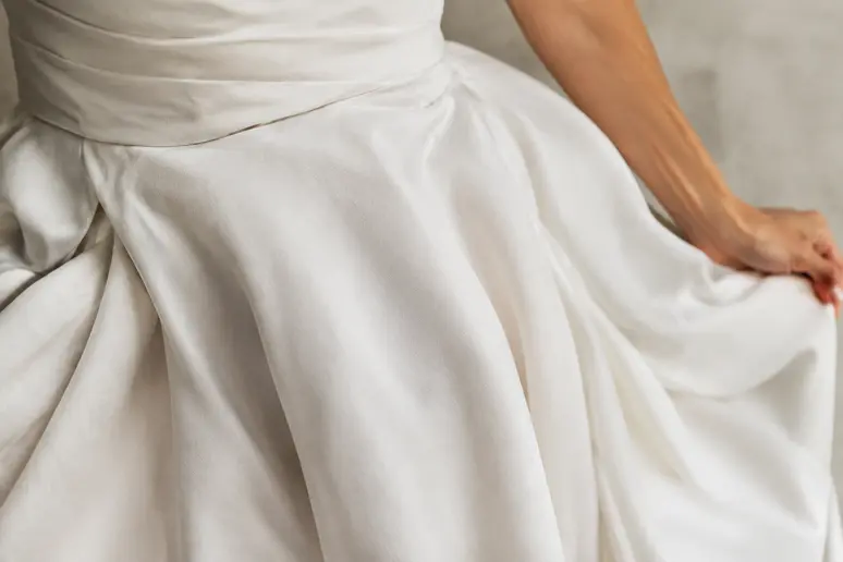 Gros plan sur le tissu fluide et les drapés soignés d'une robe de mariée épurée