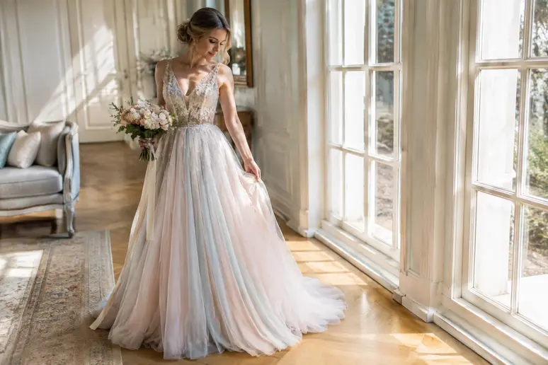 Robe de mariée colorée aux teintes pastel douces vue de près dans un intérieur baigné de lumière naturelle