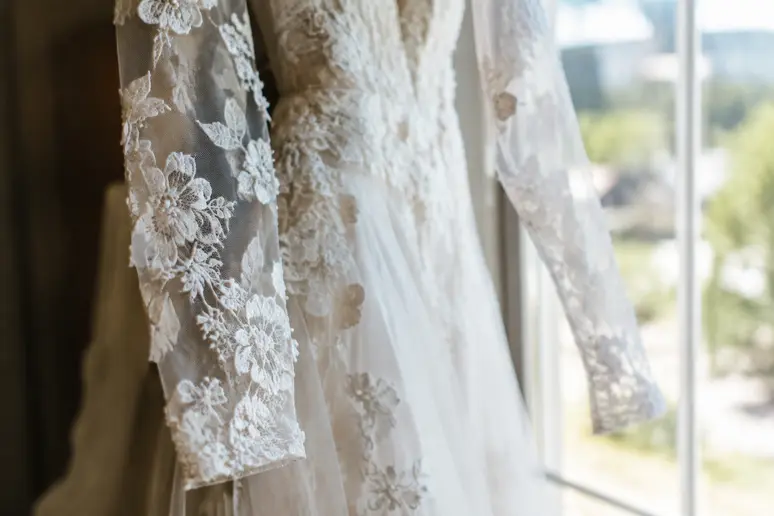 Gros plan sur les détails en dentelle transparente d'une robe de mariée manches longues
