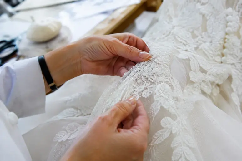 Examen minutieux des finitions en dentelle d'une robe de mariée avant les ajustements de couture