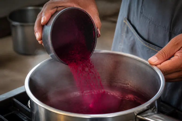 Versement de colorant pour textile synthétique dans une casserole d'eau chaude