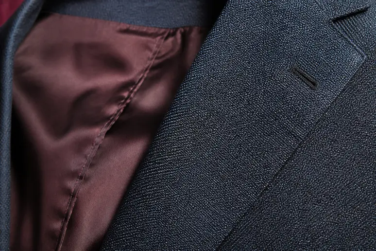 Gros plan sur la texture en laine peignée et les finitions soignées d'une veste femme habillée.